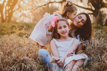 a family of three sitting in a field of tall grass